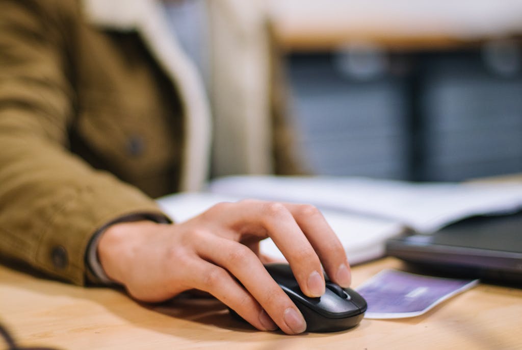 Pay Per Click 2 Focused shot of a hand operating a wireless mouse indoors at a desk.