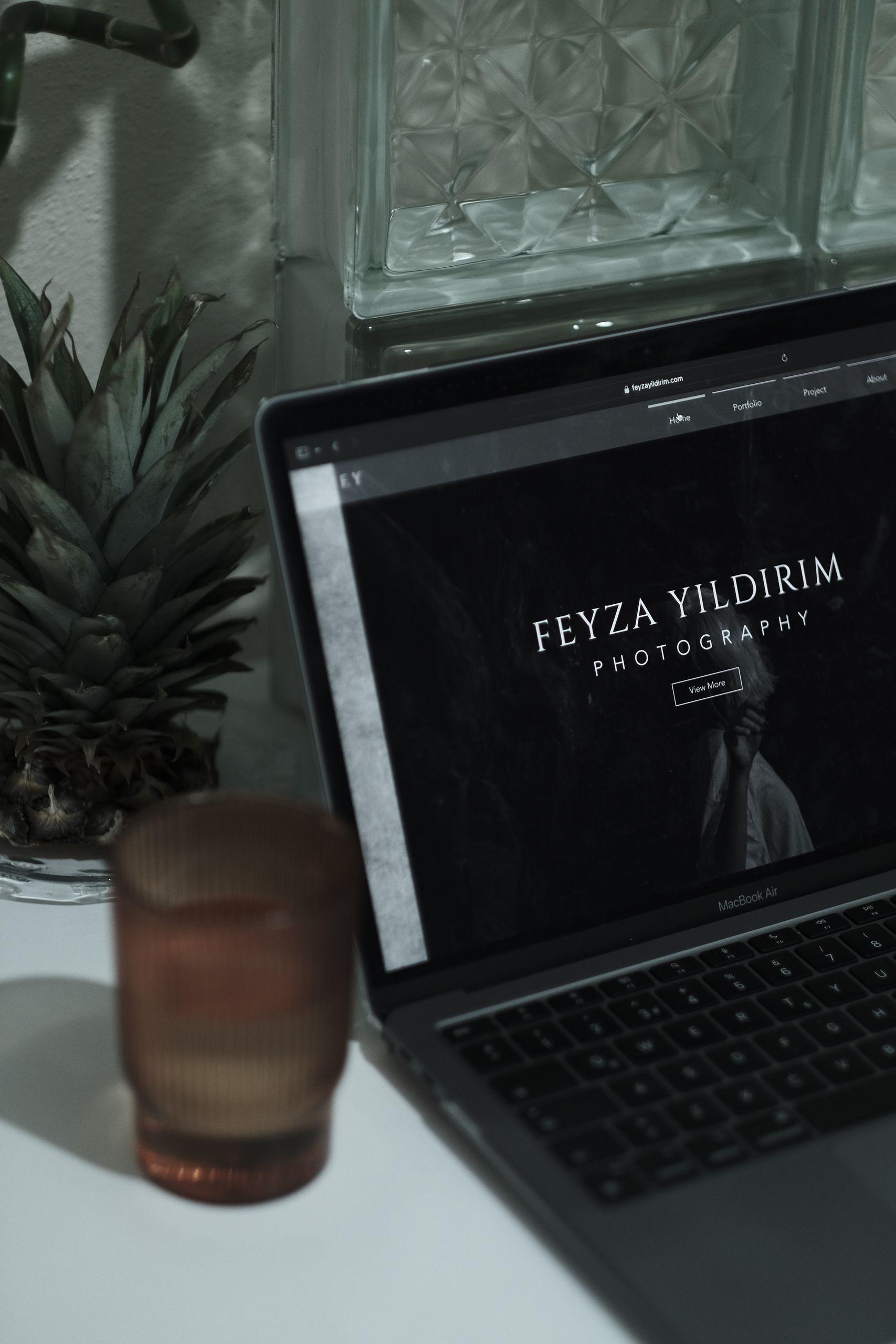 An aesthetically pleasing workspace featuring a laptop with a photographer's website, surrounded by minimalist decor.